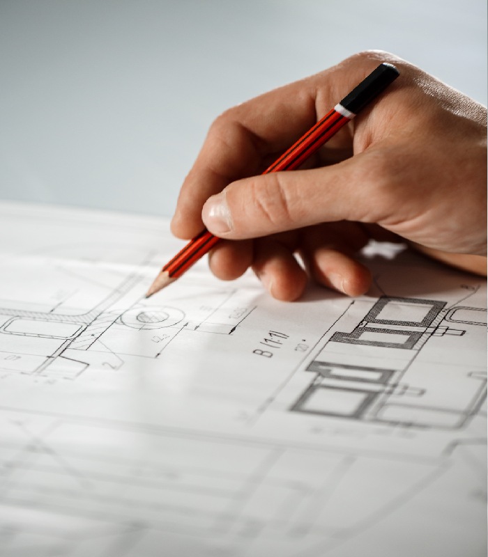Main traçant au crayon les détails d’un plan de maison.